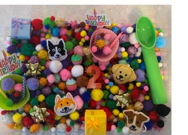 Custom birthday sensory kit filled with colorful pom poms and a number 2 candle