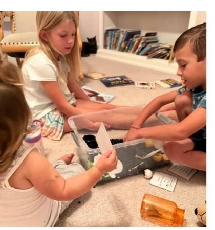 Three siblings sharing one sensory bin and taking turns